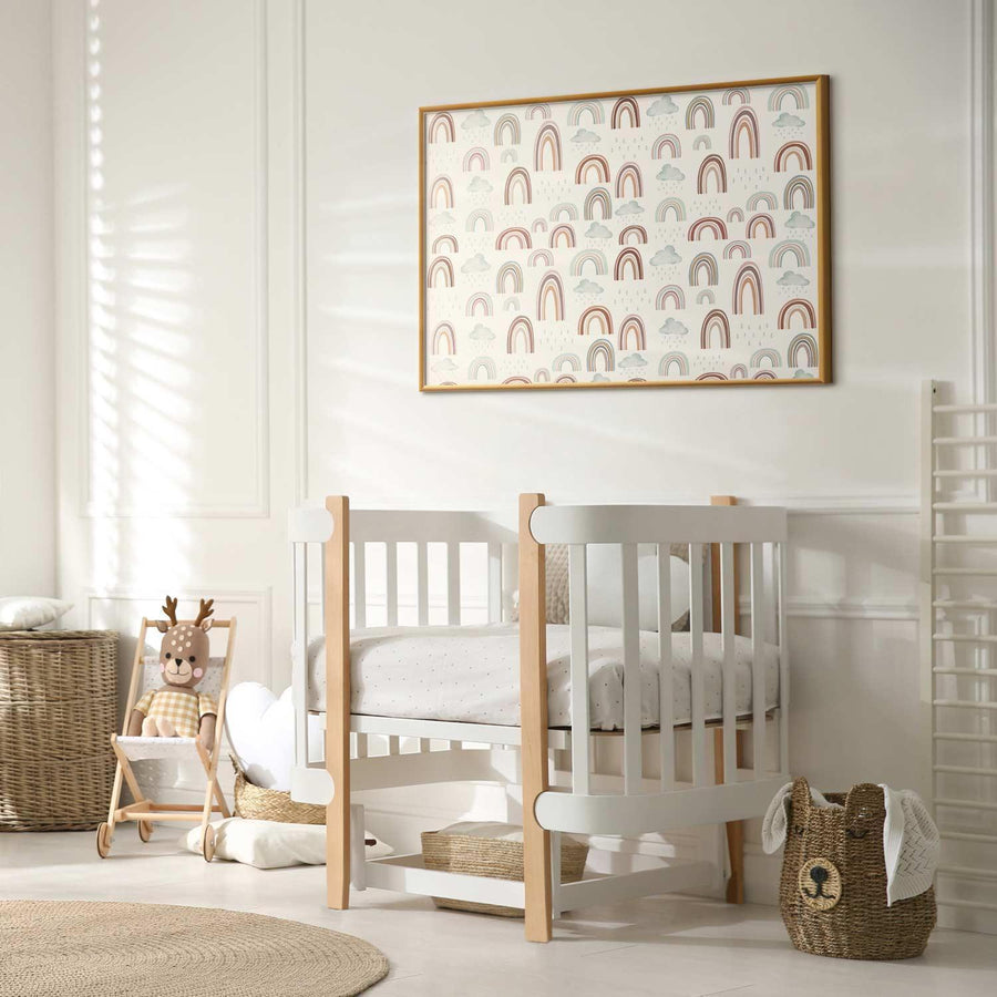 Framed poster featuring rainbow pattern hanging above white baby crib in a cozy nursery room.